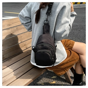 Photo lifestyle d'un sac bandoulière en nylon noir avec plusieurs poches zippées