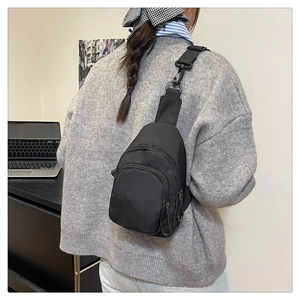 Détail d'un sac de poitrine en nylon noir avec sangle réglable et plusieurs poches zippées