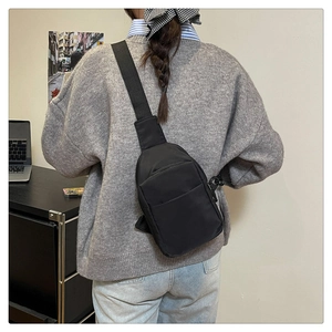 Détail du sac bandoulière en nylon noir léger avec sangle réglable et poches zippées