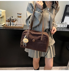 Detailed view of brown suede tote bag featuring a leather strap and fuzzy eyeball charm