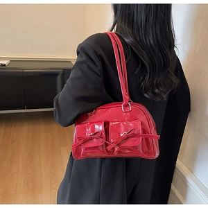 Détail du sac bandoulière en cuir verni rouge avec nœuds et poches carrées