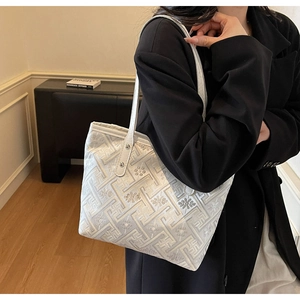 Close-up of white tote bag featuring intricate floral embroidery and leather straps