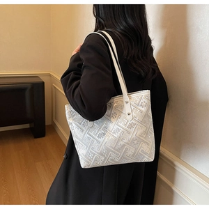 Detailed view of white ethnic tote bag with grey geometric patterns and floral textures