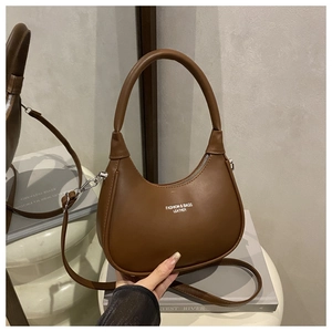 Detail view of brown leather half-moon bag featuring elegant white printed lettering