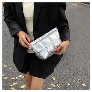 Detail of silver quilted clutch bag in high-shine metallic finish held by model