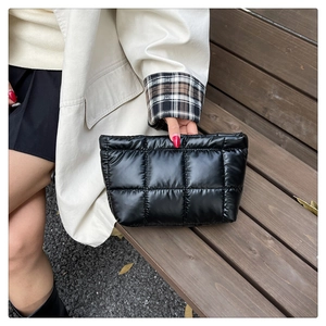 Gros plan d'un sac à main matelassé noir avec motif carré rembourré sur un banc en bois