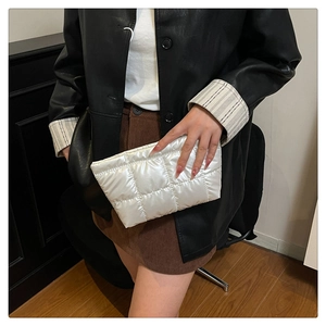 Gros plan d'un sac à main blanc matelassé en tissu imperméable brillant avec bouton en métal