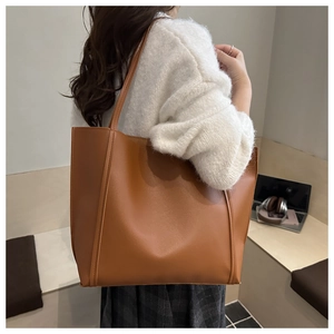 Close-up of a brown tote bag showing textured matte synthetic leather and vertical stitching