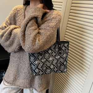Ethnic style black patterned tote bag with oversized knit sweater on a model