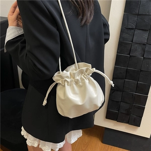 Elegante borsa a secchiello beige in morbida ecopelle con coulisse indossata da modella