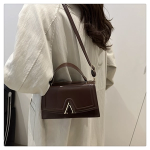 Detailed view of brown PU leather shoulder bag with stylish gold triangular hardware buckle