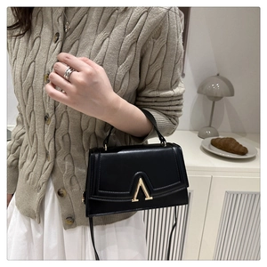Détail du sac à bandoulière noir avec fermoir en V doré et finition en cuir minimaliste