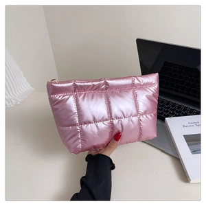 Gros plan d'une pochette matelassée rose vif avec fini métallisé et zip doré élégant