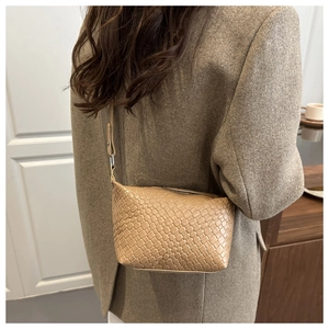 Detail of beige woven texture shoulder bag featuring metallic zipper and leather strap