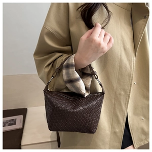 Detail of dark brown woven handbag with checkered texture and decorative fabric handle