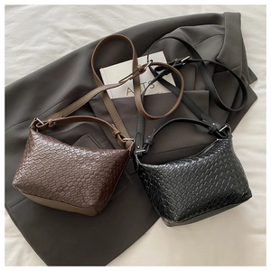Detail of woven hobo shoulder bags in brown and black on a grey suit jacket