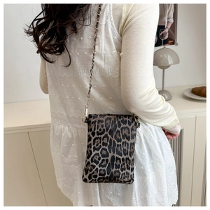 Detailed view of leopard print crossbody bag with gold chain strap on model