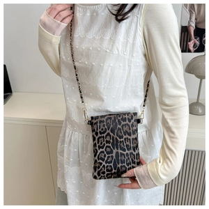 Close-up of leopard print crossbody bag featuring gold metal chain and leather strap