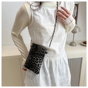 Detail of leopard print mini crossbody bag with gold metal chain strap on a model