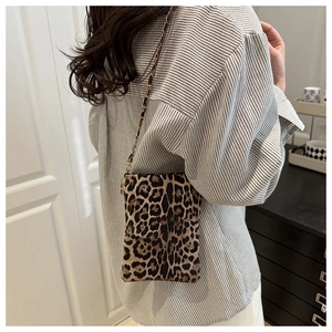 Detail of leopard print mini crossbody bag with metal chain strap on model's back