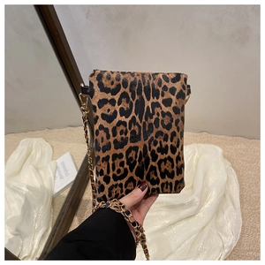 Macro detail of leopard print shoulder bag featuring gold chain strap and textured fabric