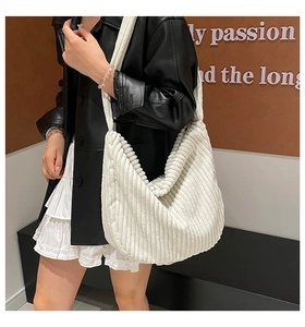 Detail of white corduroy crescent tote bag showing ribbed texture on a female model