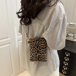 Fashionable leopard print crossbody phone bag with a gold chain strap worn by a model