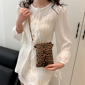 Fashionable leopard print crossbody phone bag with gold metal chain strap on white dress