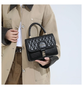 Detail of black leather handbag with vertical quilted patterns and gold metal lock
