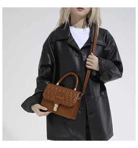 Brown handbag with quilted flap detail and fashion logo shown on model as crossbody bag