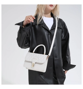 Detail of white quilted handbag featuring a golden turn-lock and fashion text tag