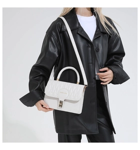 Detail of white quilted handbag with turn-lock and 'FASHION' text on model