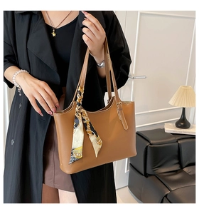 Brown leather tote bag with printed silk scarf detail shown on shoulder in lifestyle setting