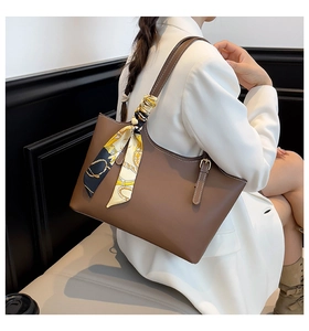 Brown leather tote bag with printed silk scarf detail shown on a model's shoulder