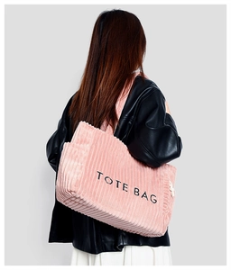 Detailed close-up of pink corduroy tote bag featuring black embroidered lettering