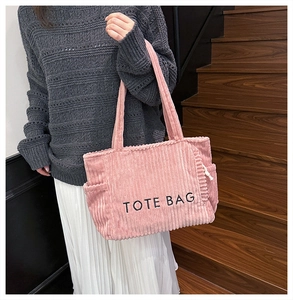 Detail of pink corduroy tote bag with TOTE BAG embroidery and side pocket feature