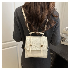 Detailed view of cream textured leather backpack with gold metal buckle and brand logo