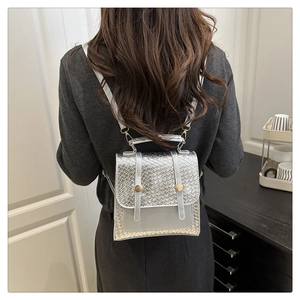 Silver woven texture backpack with golden buckles worn by a model in a modern interior