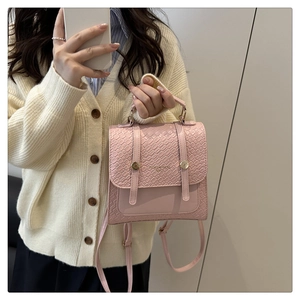 Detail of pink embossed leather handbag with gold buckles and adjustable shoulder strap