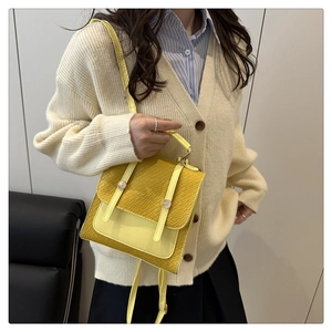 Detail of yellow crocodile embossed leather crossbody bag with decorative straps and metallic studs