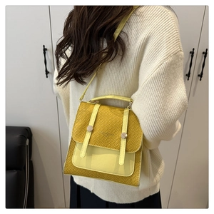 Detail of yellow crossbody bag featuring snake pattern texture and round metal buckle