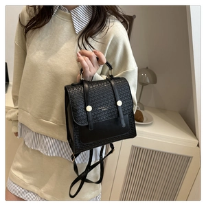 Detail of black woven texture backpack with gold hardware worn by a model in a home setting