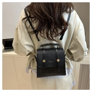 Detail of black woven texture flap and golden round buckles on the leather backpack