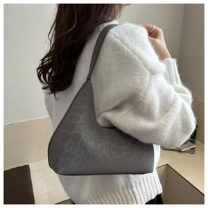 Detailansicht der grauen Schultertasche mit Leopardenmuster aus mattem Wildleder am Model