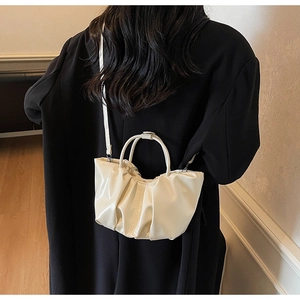 Detail of creamy pleated cloud handbag in polished faux leather with adjustable shoulder strap