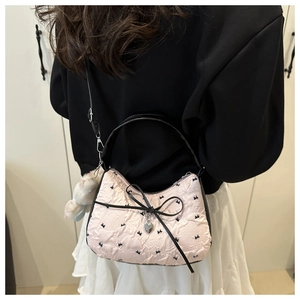 Détail d'un sac à main rose brodé avec nœud noir et pendentif cœur argenté chic