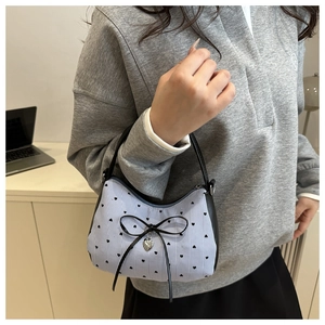 Détail du sac à main à rayures bleues avec motif cœur et nœud décoratif en cuir