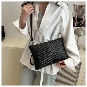 Detail of black V-quilted crossbody bag with rivet studs on matte leather finish