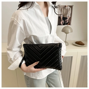 Dettaglio pochette in pelle nera con borchie argentate a V e texture trapuntata