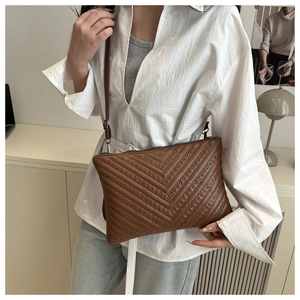 Detail of dark brown leather crossbody bag with silver studs and V-shape wave pattern